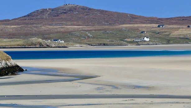 A beach with a clear view of the sea, a sandy shore, and a hill with a structure on top. - Private  Croft House in the Western Isles 
STL Licence Number ES00069F (Scotland)