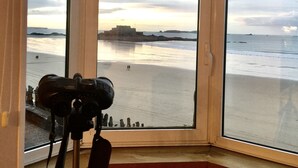 A room with a large bay window overlooking a beach.