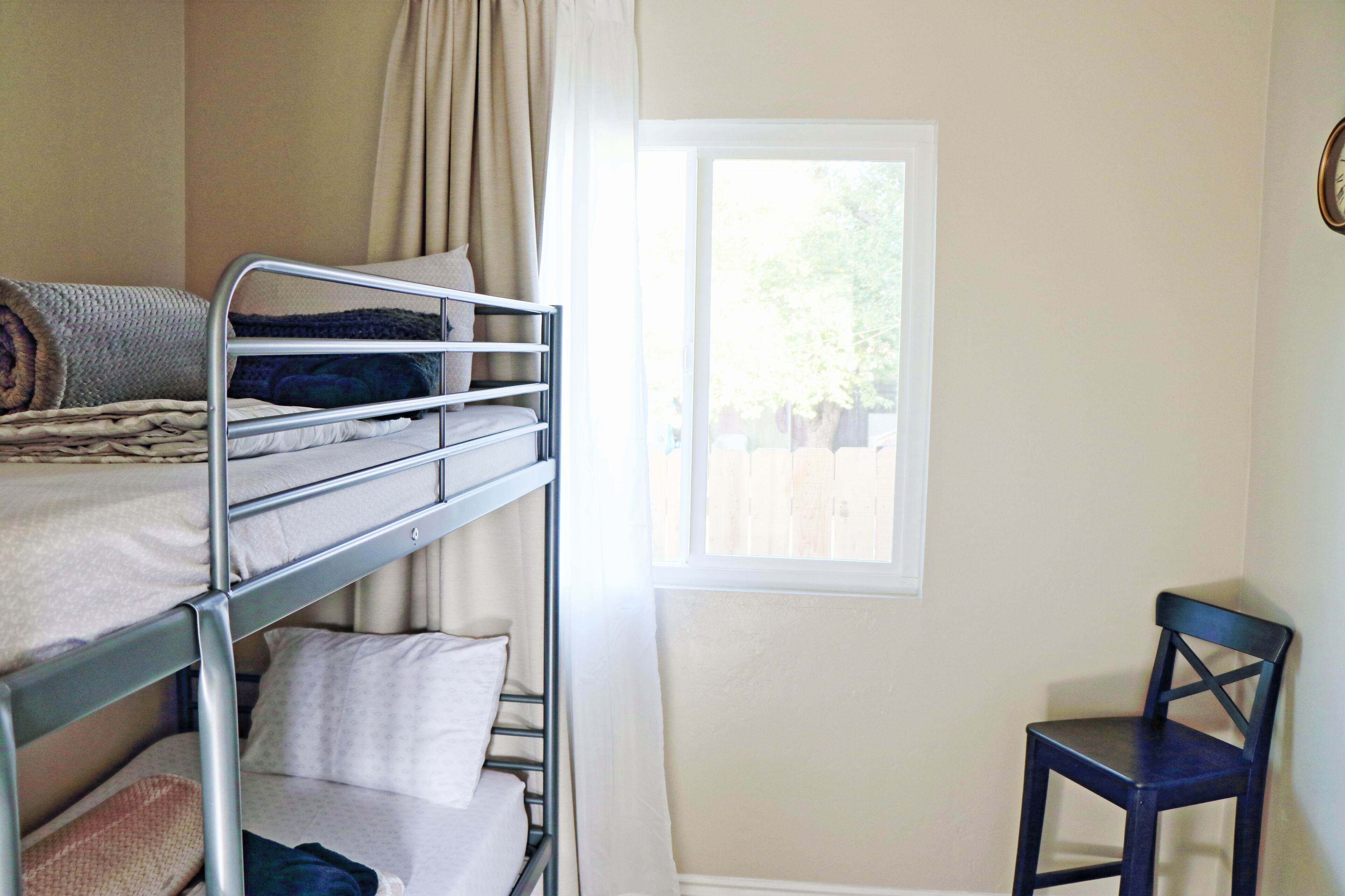 A bunk bed with a window, a chair, and a curtain.