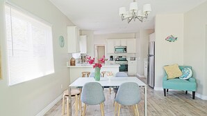 A modern kitchen with white cabinets, a stainless steel refrigerator, and a dining area with a white table and grey chairs. - 4bd / 2bth private parking, 8 min to Gaslamp, Zoo (San Diego)