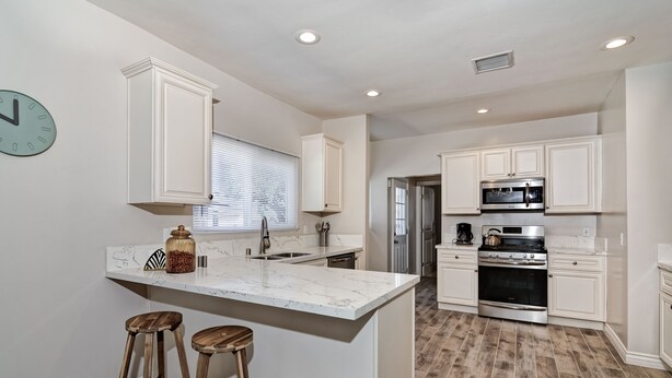 A modern kitchen with white cabinetry, a marble countertop, and two wooden stools. - 4bd / 2bth private parking, 8 min to Gaslamp, Zoo (San Diego)