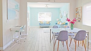A bright living room with a blue sofa, a dining table with chairs, and a white desk with a chair. - 4bd / 2bth private parking, 8 min to Gaslamp, Zoo (San Diego)