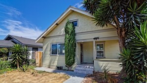 A single-story house with a front porch, a tall evergreen tree, and a well-maintained lawn. - 4bd / 2bth private parking, 8 min to Gaslamp, Zoo (San Diego)