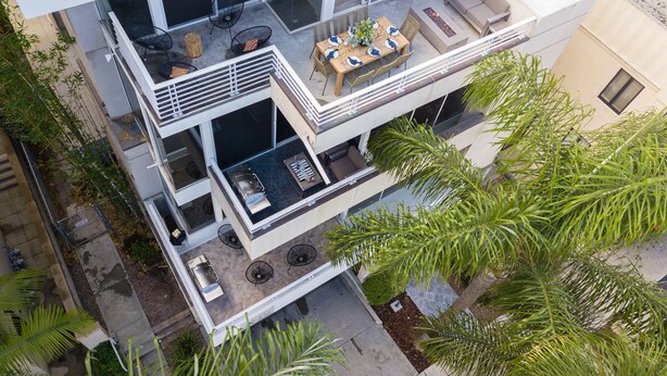 A multi-level residential building with a balcony, outdoor seating, and a pool area.