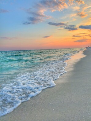 Ein Strand mit sanften Wellen und einem Sonnenuntergangshimmel.