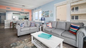 A living room with two grey sofas, a white coffee table, and a colorful rug.