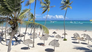 Perto da praia, areia branca, espreguiçadeiras, guarda-sóis