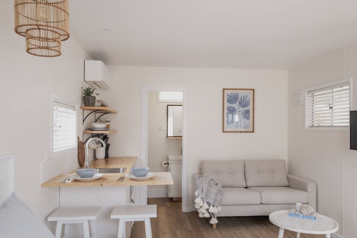 Un espace de vie moderne et minimaliste comprenant un coin cuisine, un canapé et une petite table à manger.
