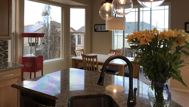 A kitchen with a granite countertop, a sink, a red appliance, and a dining area with chairs and a table.