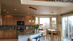 A spacious kitchen with wooden cabinets, a central island, and pendant lighting.