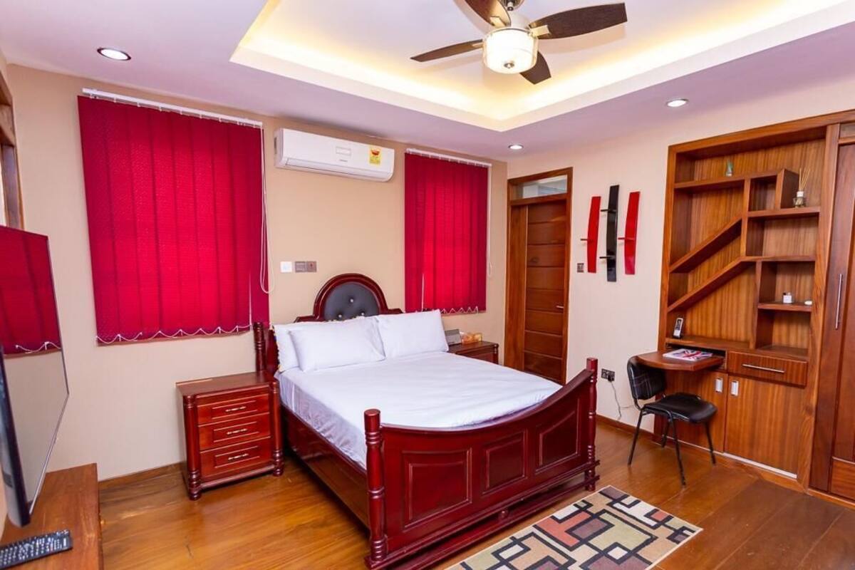 Um quarto com uma cama de madeira, uma escrivaninha, uma cadeira e um guarda-roupa.