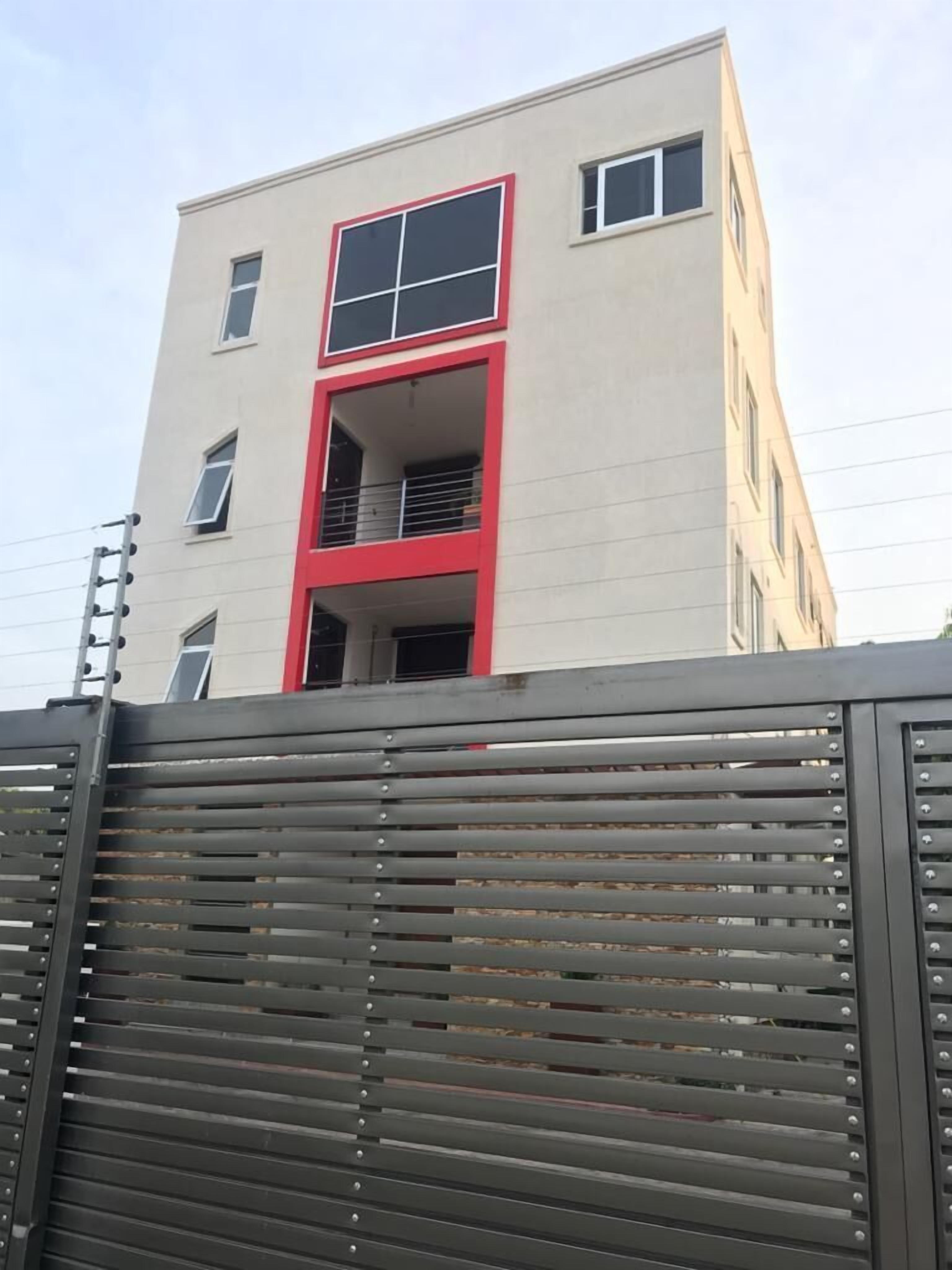 Un edificio de varios pisos con un diseño moderno, que destaca por su llamativo esquema de color rojo y blanco.