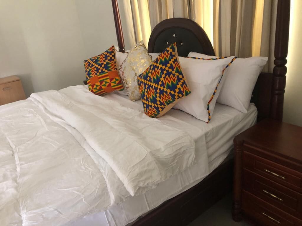A neatly made bed with white linens, a wooden headboard, and decorative pillows in geometric patterns.