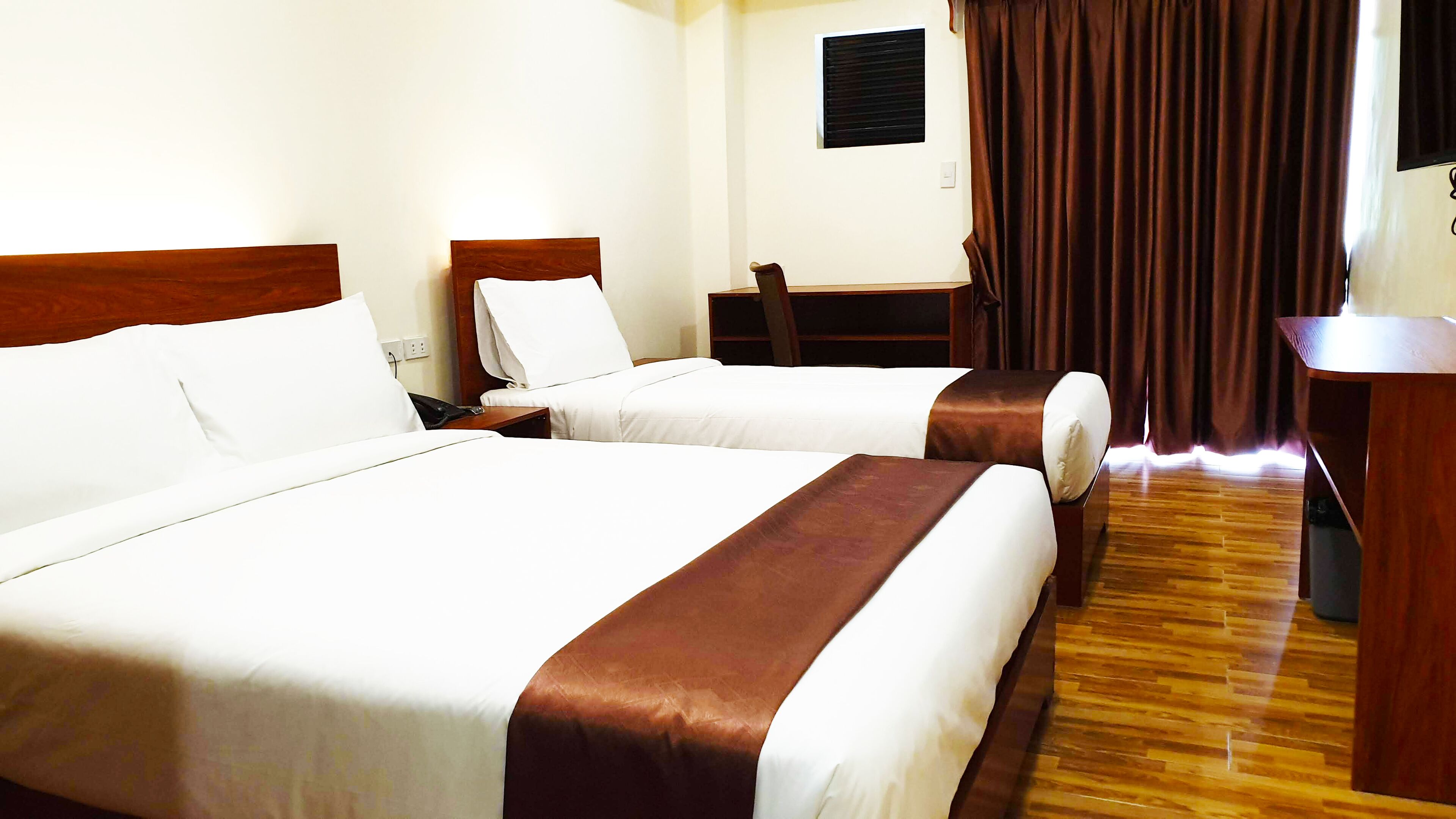 A hotel room with two beds, a desk, and a chair.