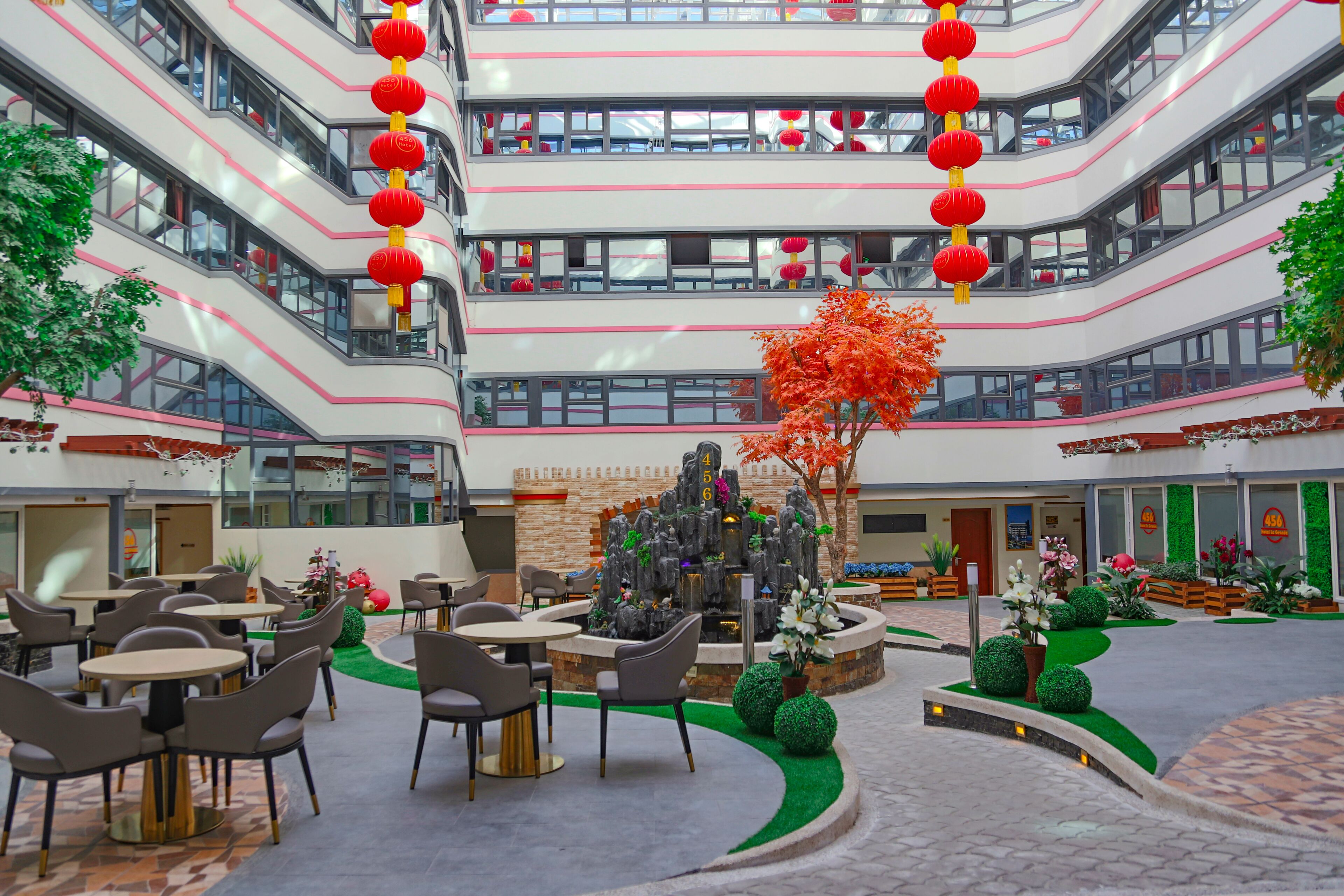 A multi-level atrium with outdoor seating, a central decorative fountain, and red lanterns.