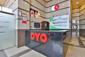 Ein Empfangsschalter mit dem OYO-Logo, einem gerahmten Zertifikat und einem Schild mit arabischer Schrift.