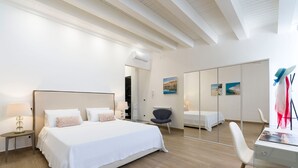 A modern bedroom with a large bed, a desk, and a chair. There is a mirror on the wall and a window with curtains. - Luxury villa with pool situated near Ribera, Agrigento, Sicily – 6 pax (Ribera)