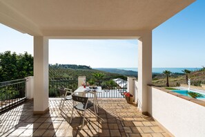 A balcony with a table and chairs, overlooking a pool and a scenic landscape. - Luxury villa with private pool near Ribera - DiCasaInSicilia (Ribera)