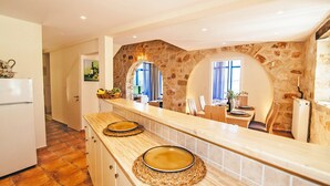 A kitchen with a stone wall, a wooden counter, and a refrigerator. - 3 Bedroom Villa, Agios Sostis, Zakynthos (Lithakia)