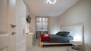 Ein modernes Schlafzimmer mit Bett, Nachttisch und einem an der Wand befestigten Fernseher.
