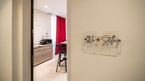 Ein Flur mit einem Wandschild mit der Aufschrift 'B&B Stella' und einem Blick auf einen Essbereich mit roten Vorhängen.