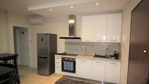 Eine moderne Küche mit weißen Schränken, einem Edelstahl-Kühlschrank, einem Einbauofen und einer gefliesten Spritzschutzwand.