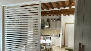 A modern kitchen with white cabinets, a dining table, and a green stool.