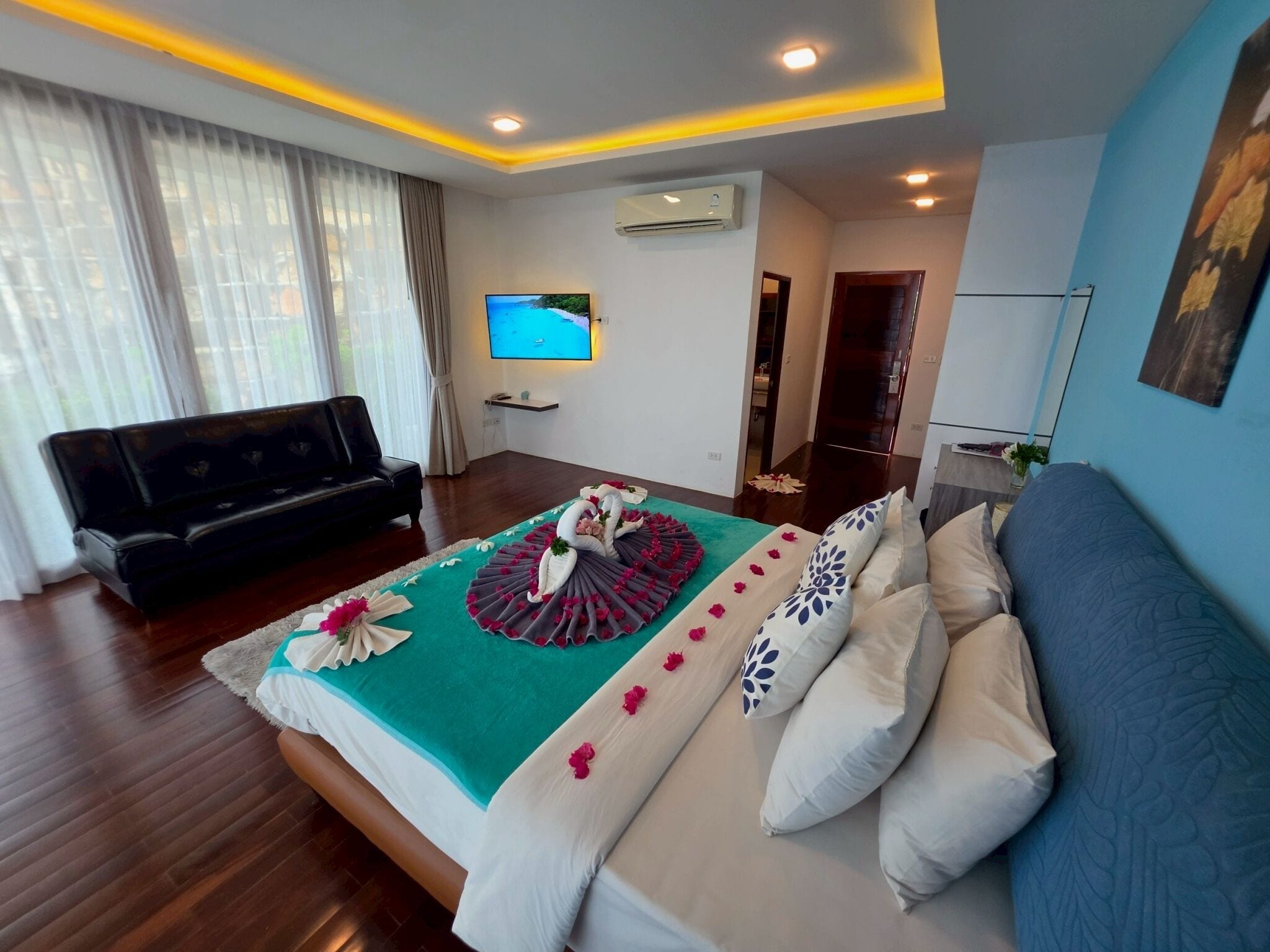 Una habitación de hotel con cama, sofá, televisión y aire acondicionado.
