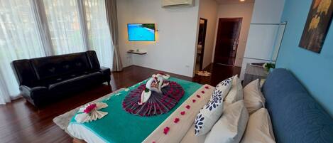 Una habitación de hotel con cama, sofá, televisión y aire acondicionado.