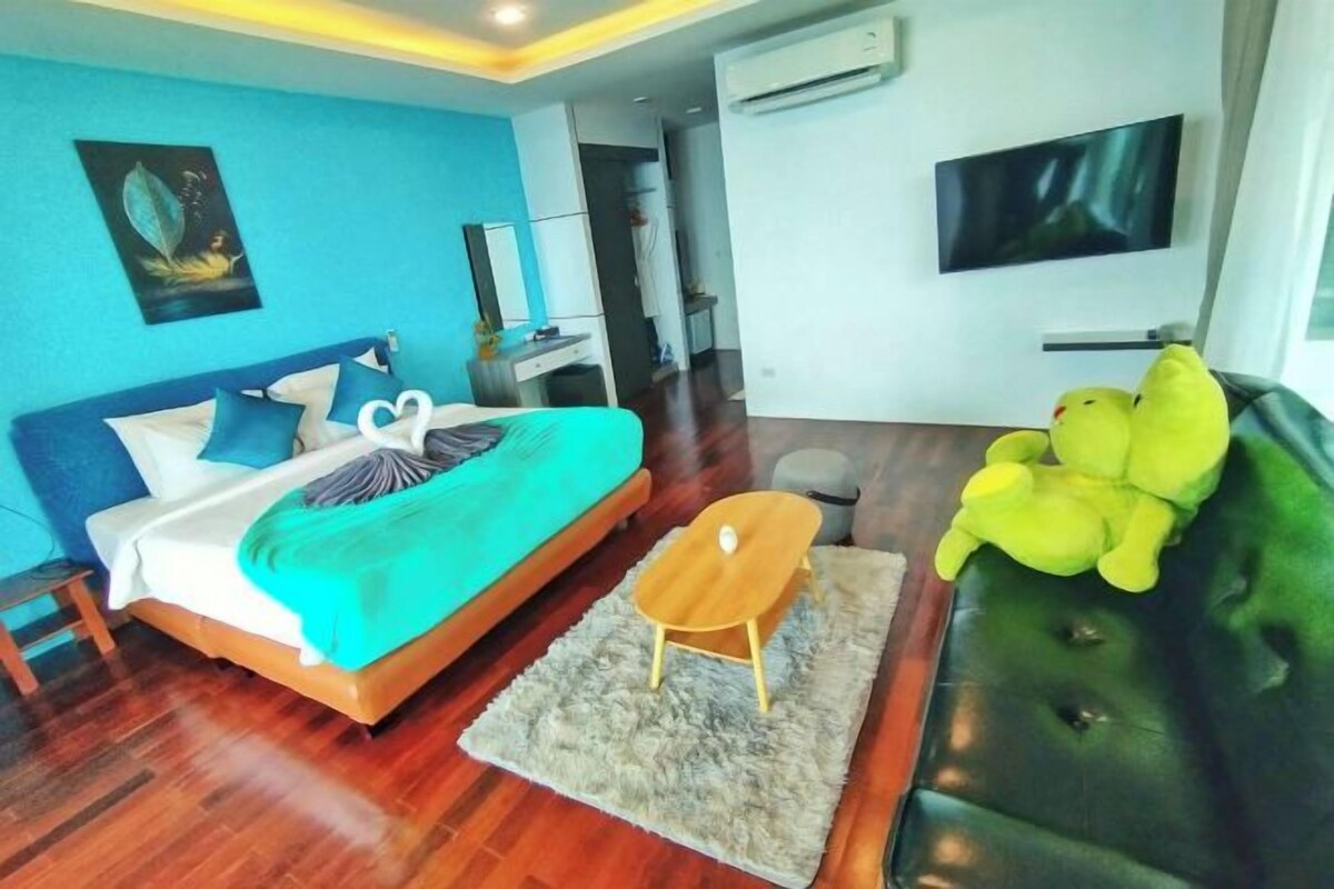 A modern bedroom with a bed, a green sofa, and a TV.
