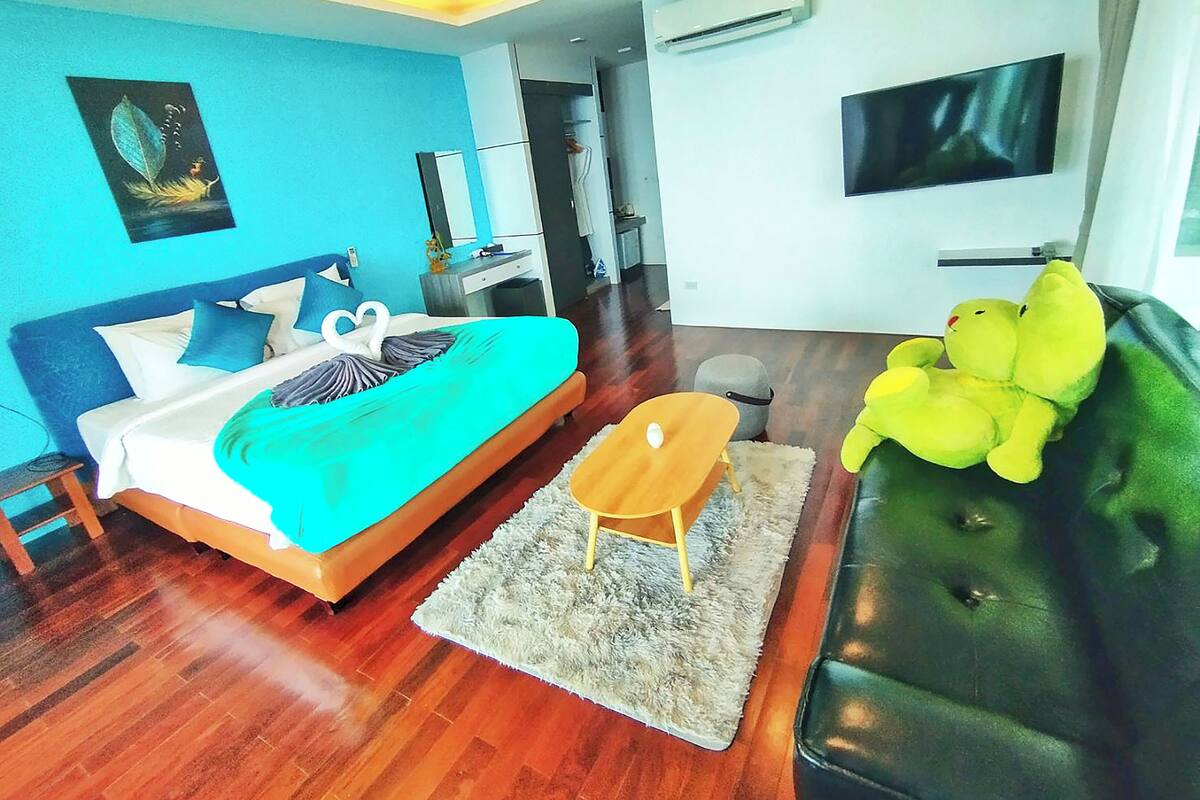 Un dormitorio moderno con cama, sofá, mesita y televisor.