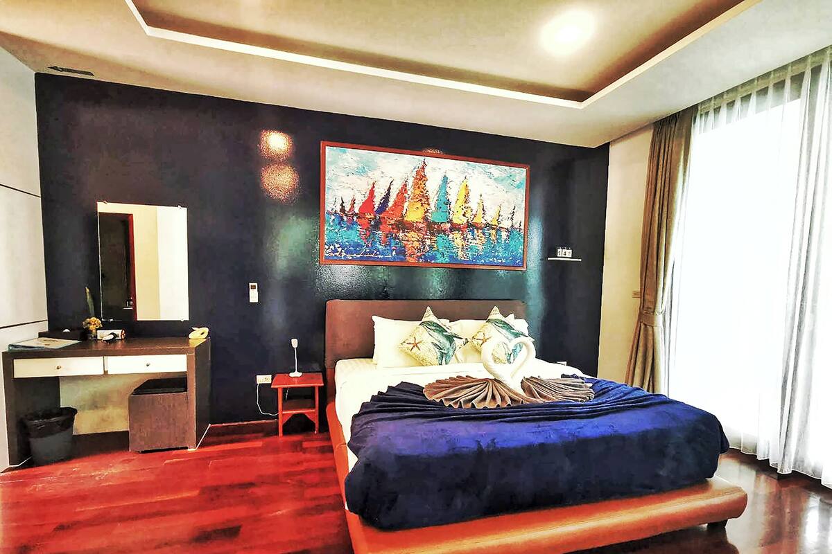 Una habitación de hotel con una cama grande, un escritorio con espejo y un cuadro en la pared.