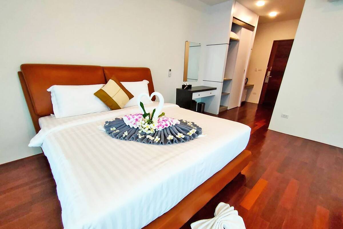Una habitación de hotel con una cama grande, un cabecero de madera, una mesita de noche y un espejo.