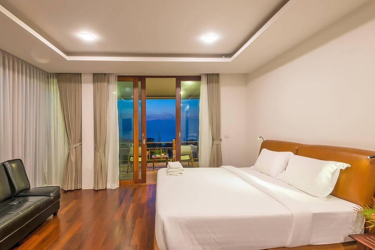 Habitación de hotel con cama, sofá y balcón con vistas.