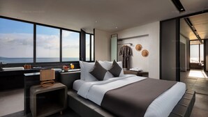 Ein modernes Hotelzimmer mit einem großen Bett, einem Nachttisch, einem Spiegel und Meerblick.