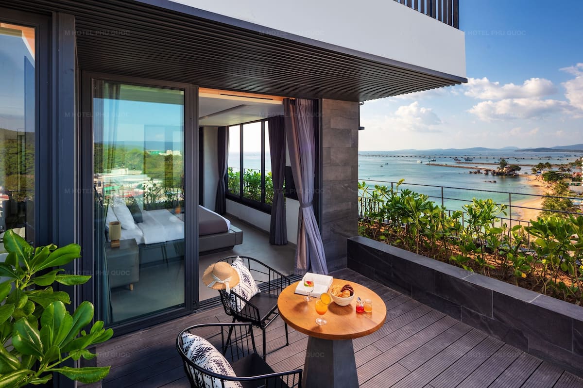 A modern outdoor seating area with a table, chairs, and a view of the sea.
