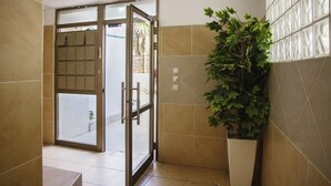 A hotel entrance with a sliding glass door, a potted plant, and tiled walls. - GK Apartments - Ben Gurion 105 (Bat Yam)