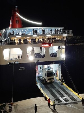Um ferry com vários níveis, uma chaminé vermelha destacada e um número IMO visível.