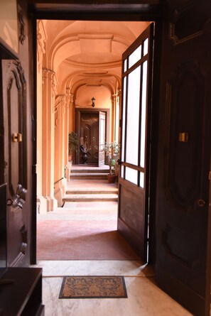 A corridor with a wooden door, a potted plant, and a lamp. - Costigliola Baroque Palace APT next MANN (Napoli)