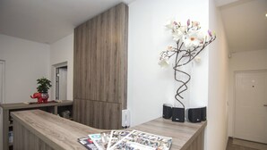 A reception desk with magazines, a decorative orchid branch, and speakers. - Beo Green View (Belgrade)