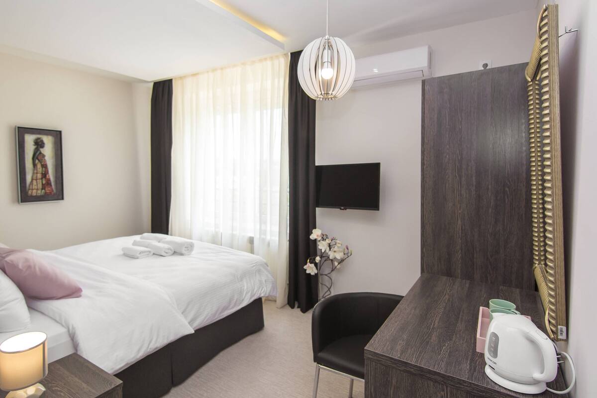 Une chambre d’hôtel équipée d’un lit, d’un bureau, d’une chaise, d’une télévision et d’un miroir décoratif.