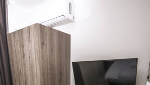 A compact hotel room with a wooden desk, a flat-screen TV, a small refrigerator, and a black chair. - Beo Green View (Belgrade)