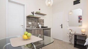 A modern kitchen with a glass dining table, a brick backsplash, and a hanging light fixture. - Beo Green View (Belgrade)