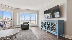 Una habitación amplia con ventanas grandes, un sillón cómodo, una mesa de comedor y un armario azul.