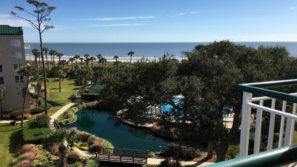 Un resort con piscina, palmeras y vista al océano.