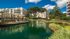 A hotel with a swimming pool, lounge chairs, and a well-maintained garden.