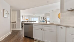 Una cocina moderna con armarios blancos, lavavajillas y un comedor con mesa y sillas.