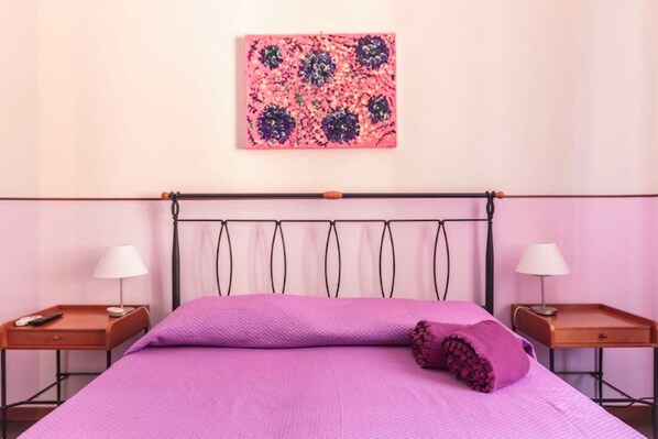 A room with a bed, two nightstands, a wall-mounted artwork, and a window.