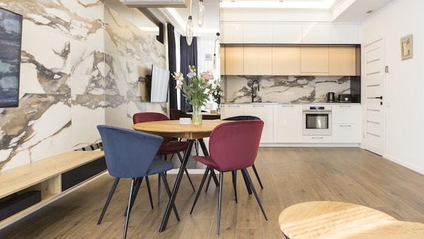 Eine moderne Küche mit Marmorfliesenspiegel, ein Essbereich mit Holztisch und Stühlen sowie eine integrierte Sitzbank.