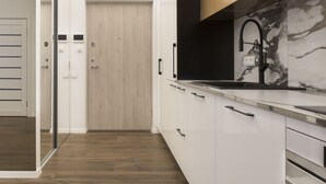 Eine moderne Küche mit weißen Schränken, einer Marmor-Spritzschutzwand und einem schwarzen Wasserhahn.